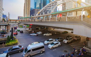 Busy city intersection in Singapore with multiple cars and a pedestrian overhead bridge.