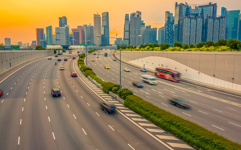 Cars navigating a busy Singapore expressway toward the city skyline.