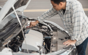 Man checking car engine to perform routine vehicle maintenance.