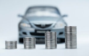 Stacks of coins in front of a blurred car.