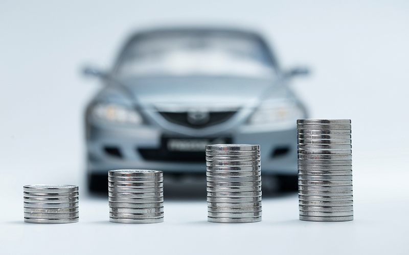 Stacks of coins in front of a blurred car.